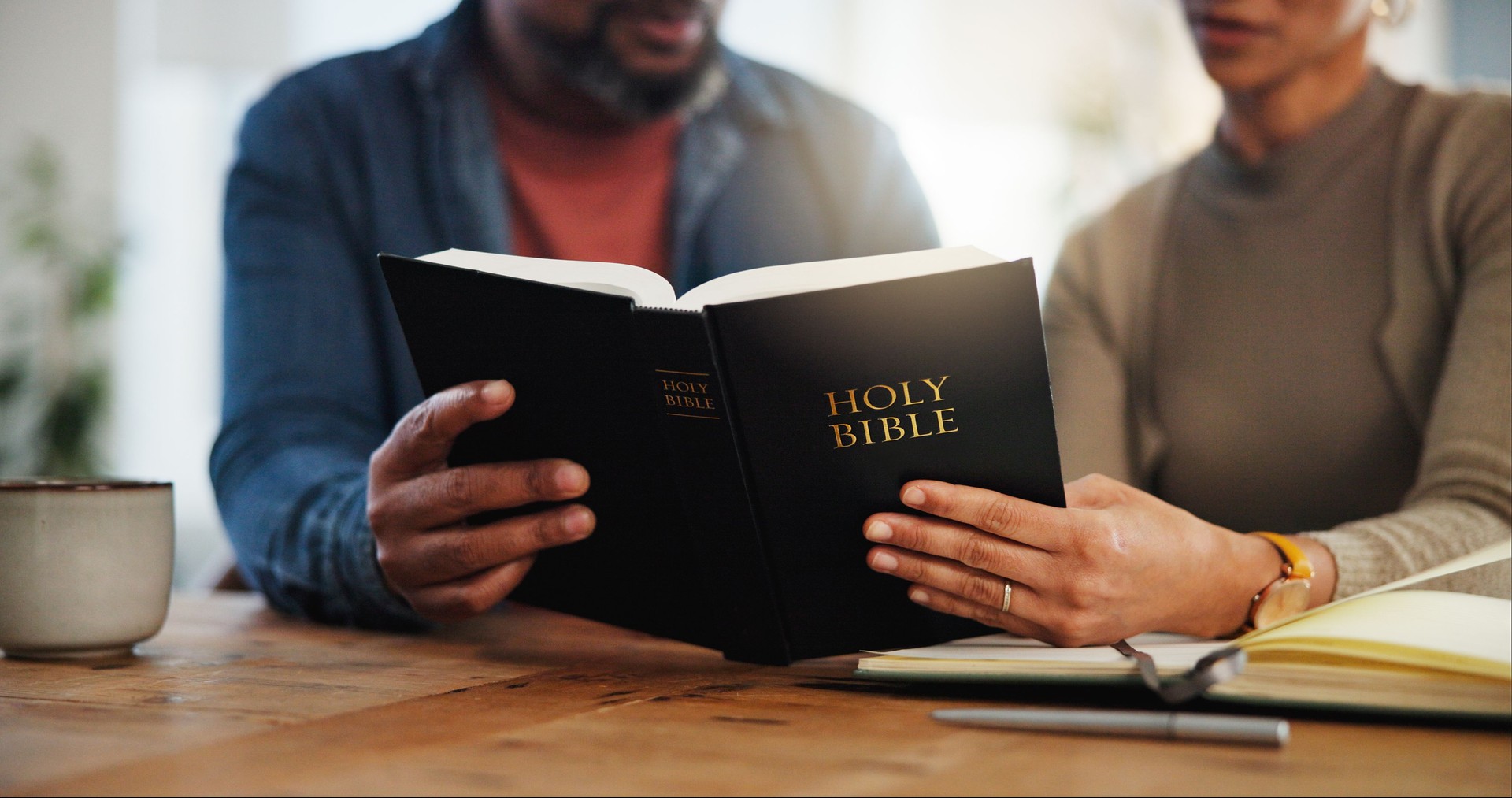 Couple, people and hands with reading bible for religious or spiritual guidance, belief and knowledge. Relationship, love and Christians with scripture or verse on holy book to worship at home